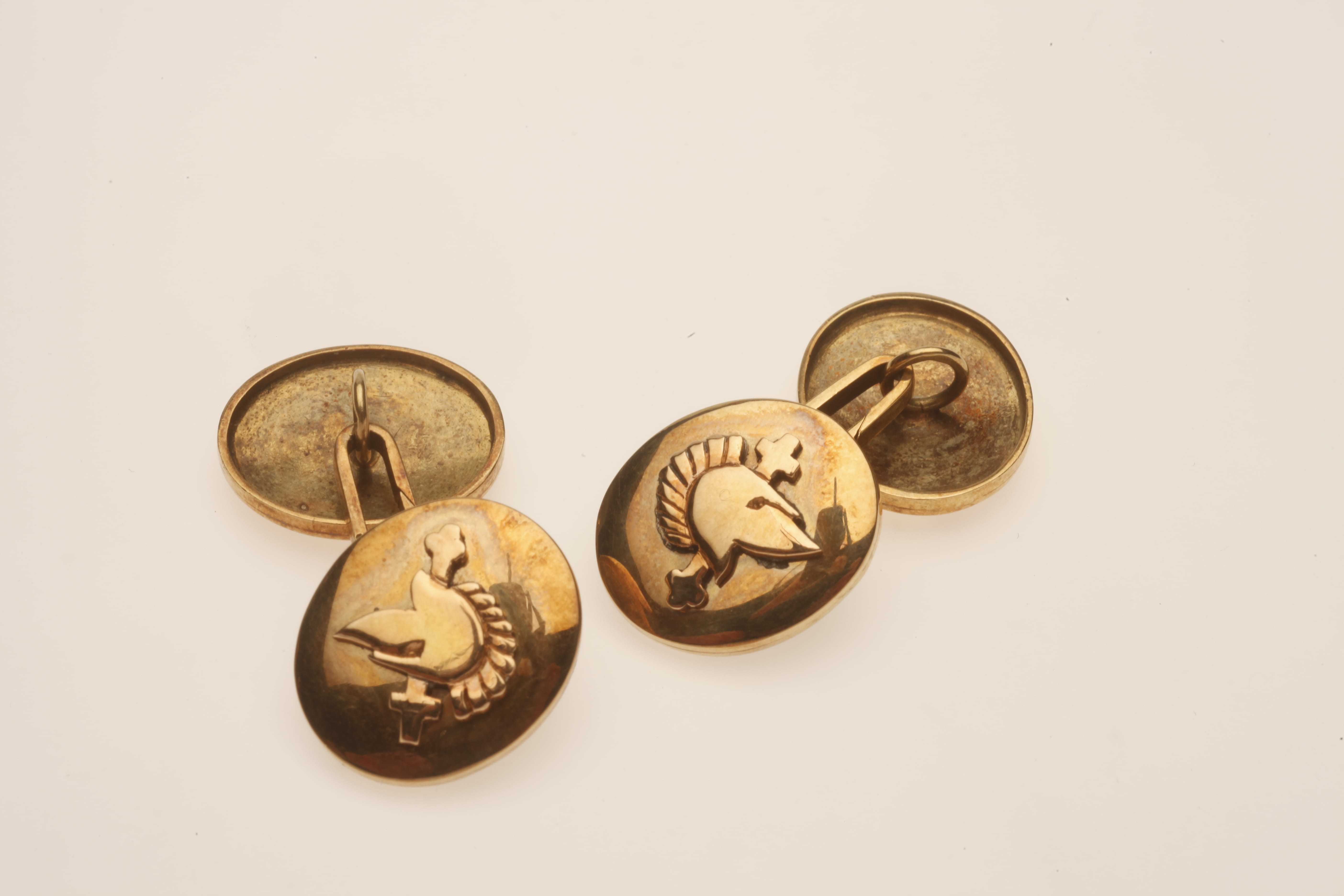 A set of gold cufflinks each displaying a spartan helmet